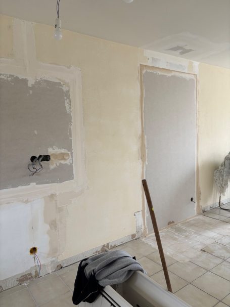 Mur en cours de rénovation avec espaces non peints et délimitations de portes.