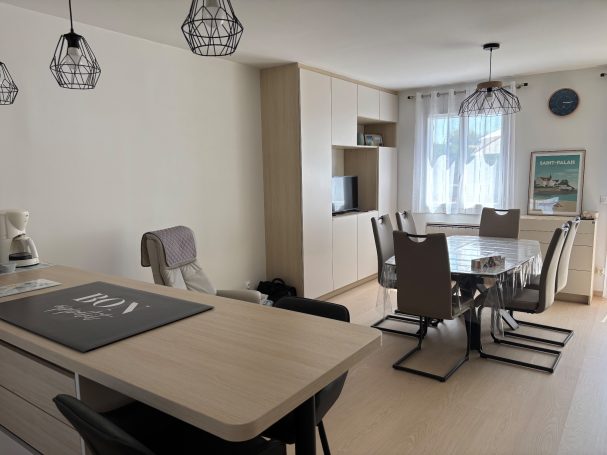 Intérieur moderne d'une cuisine-salle à manger avec mobilier élégant et éclairage suspendu.